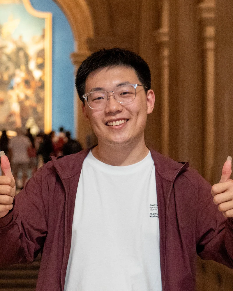 Qianxu holding both thumbs up in an ornate hall