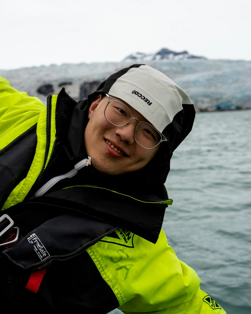 Qianxu in a yellow jacket on the water near a glacier