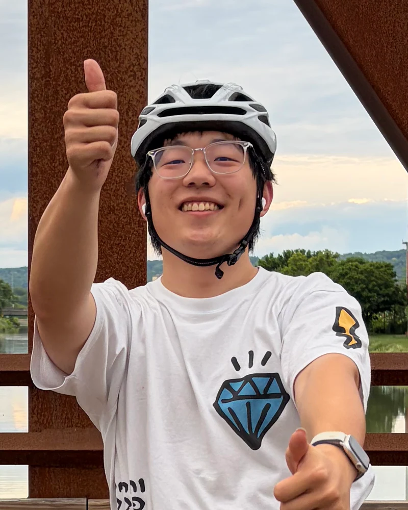 Qianxu wearing a cycling helmet and giving a thumbs up